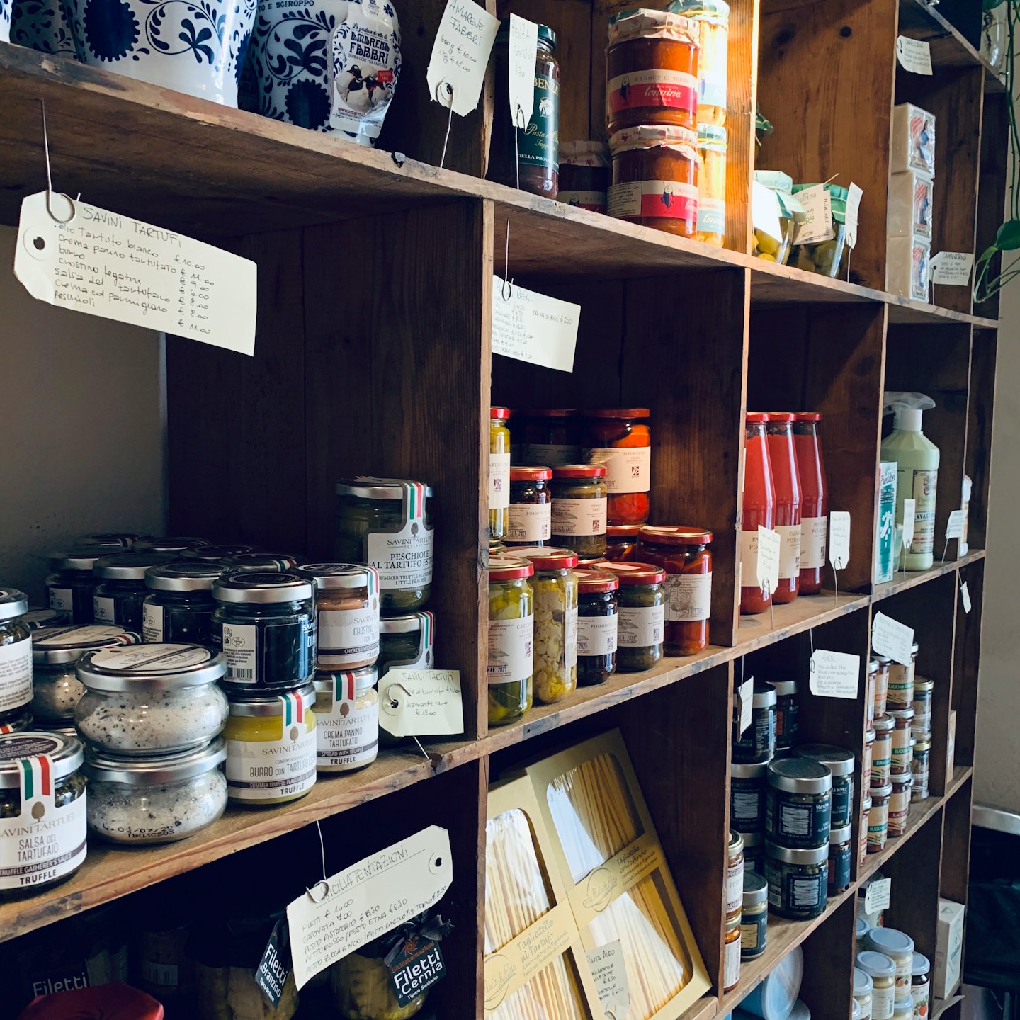Scaffali rustici pieni di prodotti alimentari artigianali italiani.