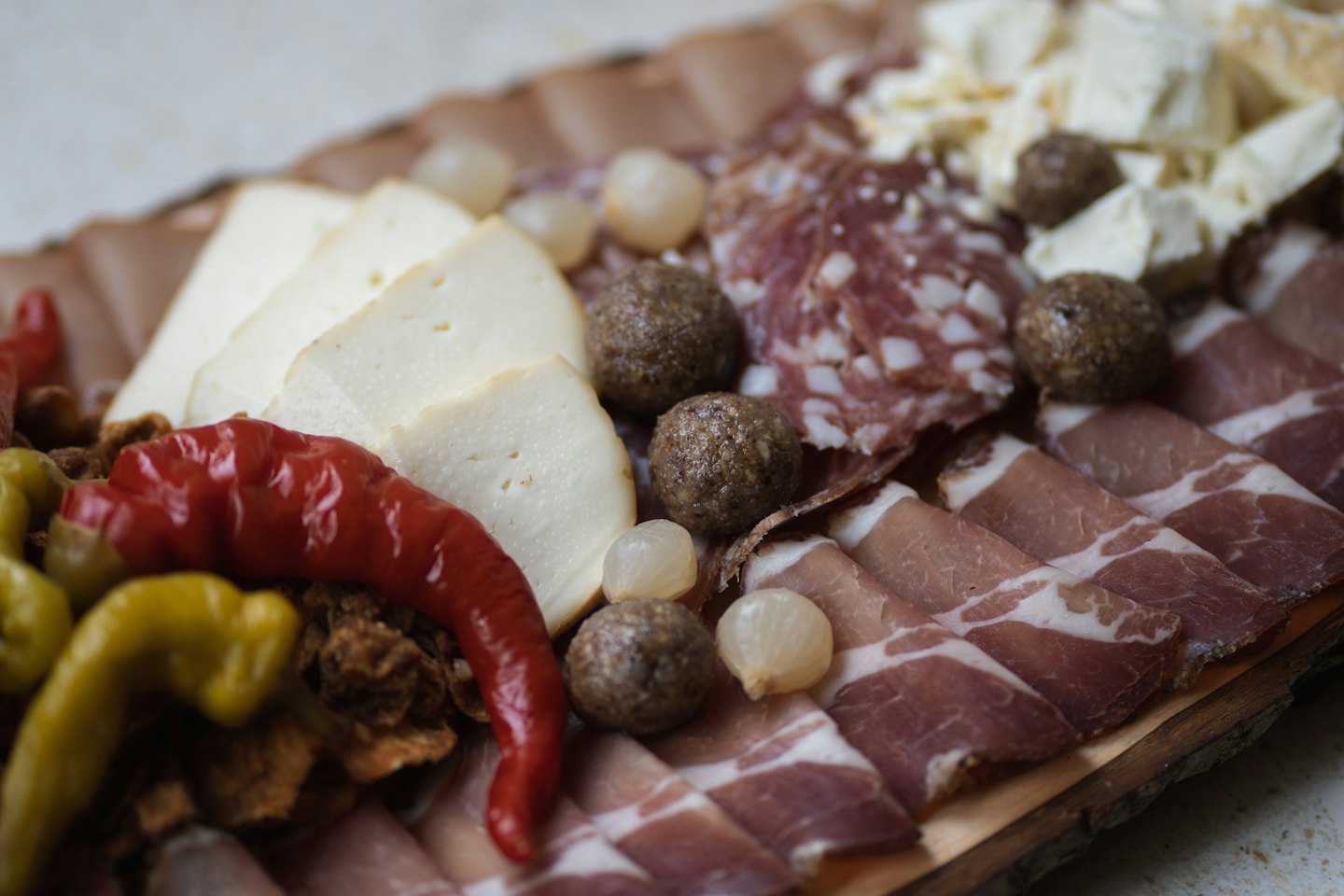 Salumi e formaggi disposti su un tagliere rustico di legno.