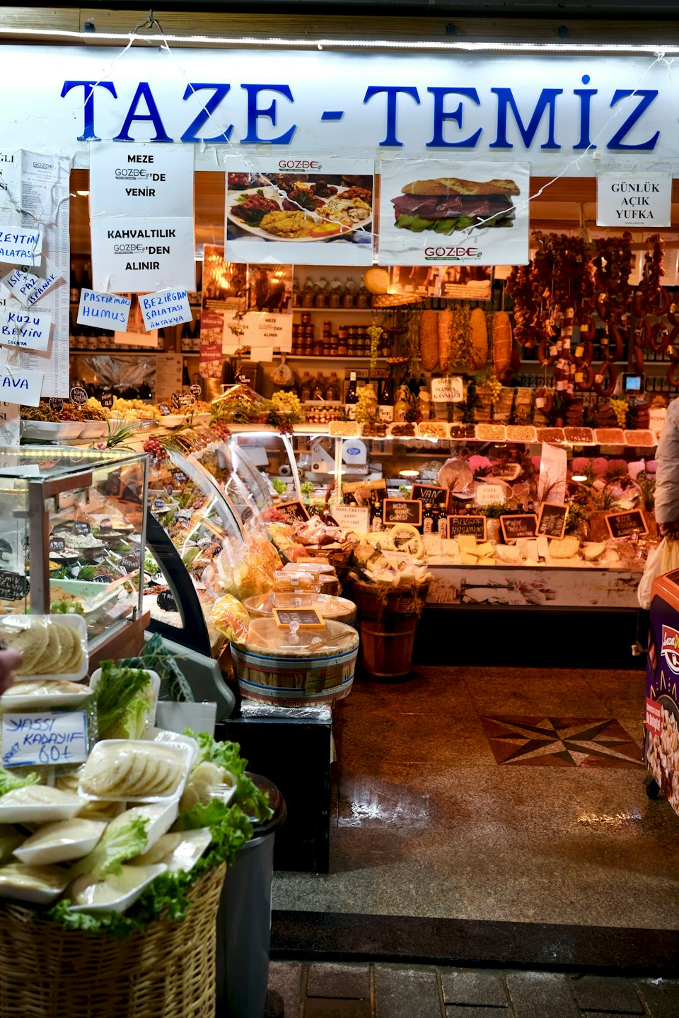 Un banco del mercato espone formaggi freschi, salumi e verdure.