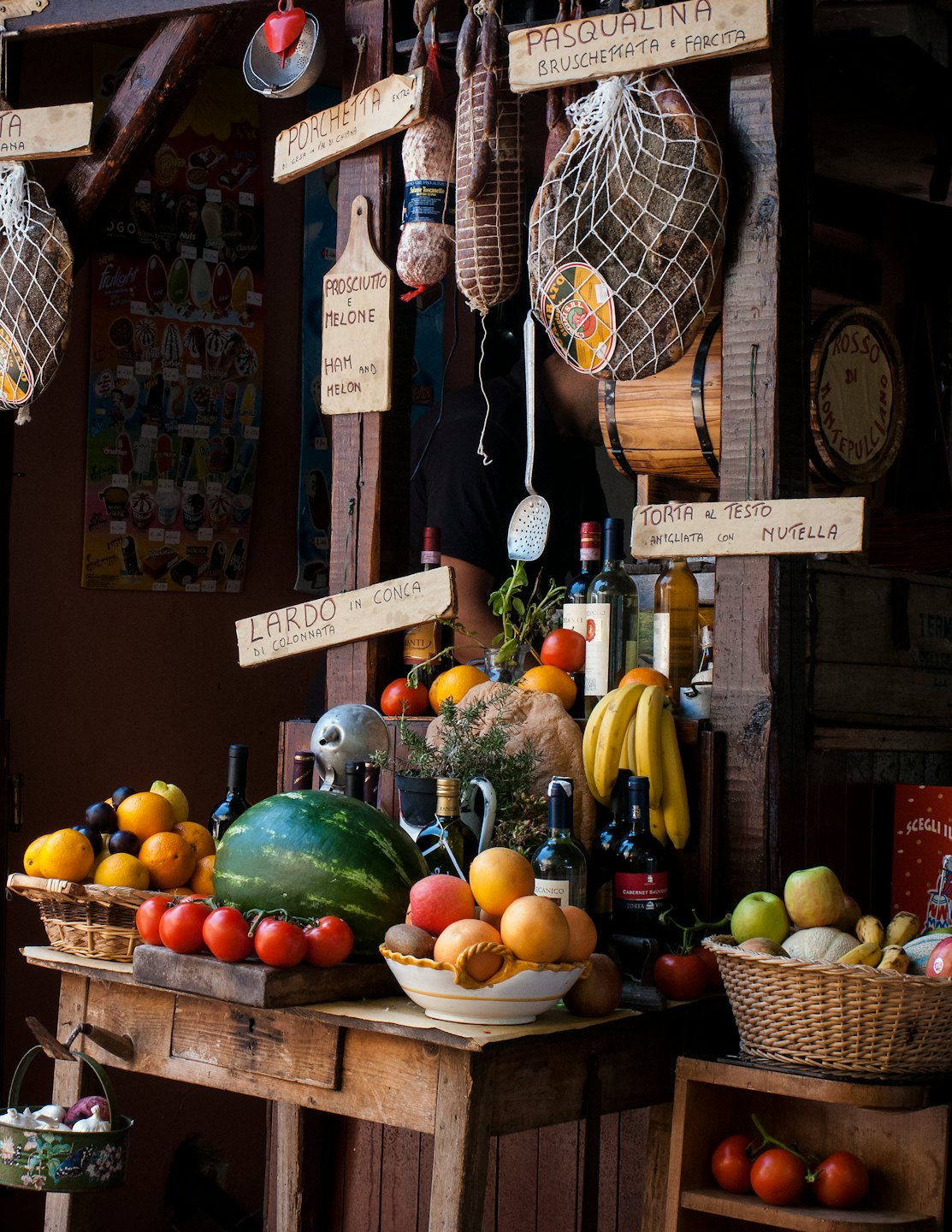Una bancarella del mercato italiano con frutta fresca e salumi.
