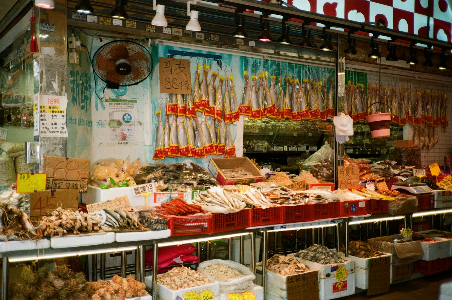 Una bancarella del mercato espone pesce secco e prodotti in cassette.